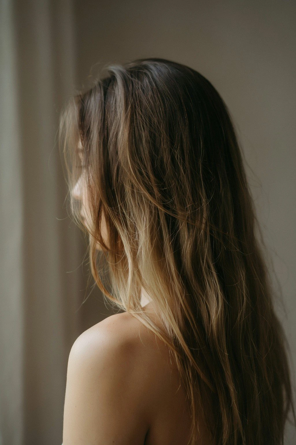 Back of a woman's head showing rich brunette hair with warm dimensional color through the mid-lengths and ends