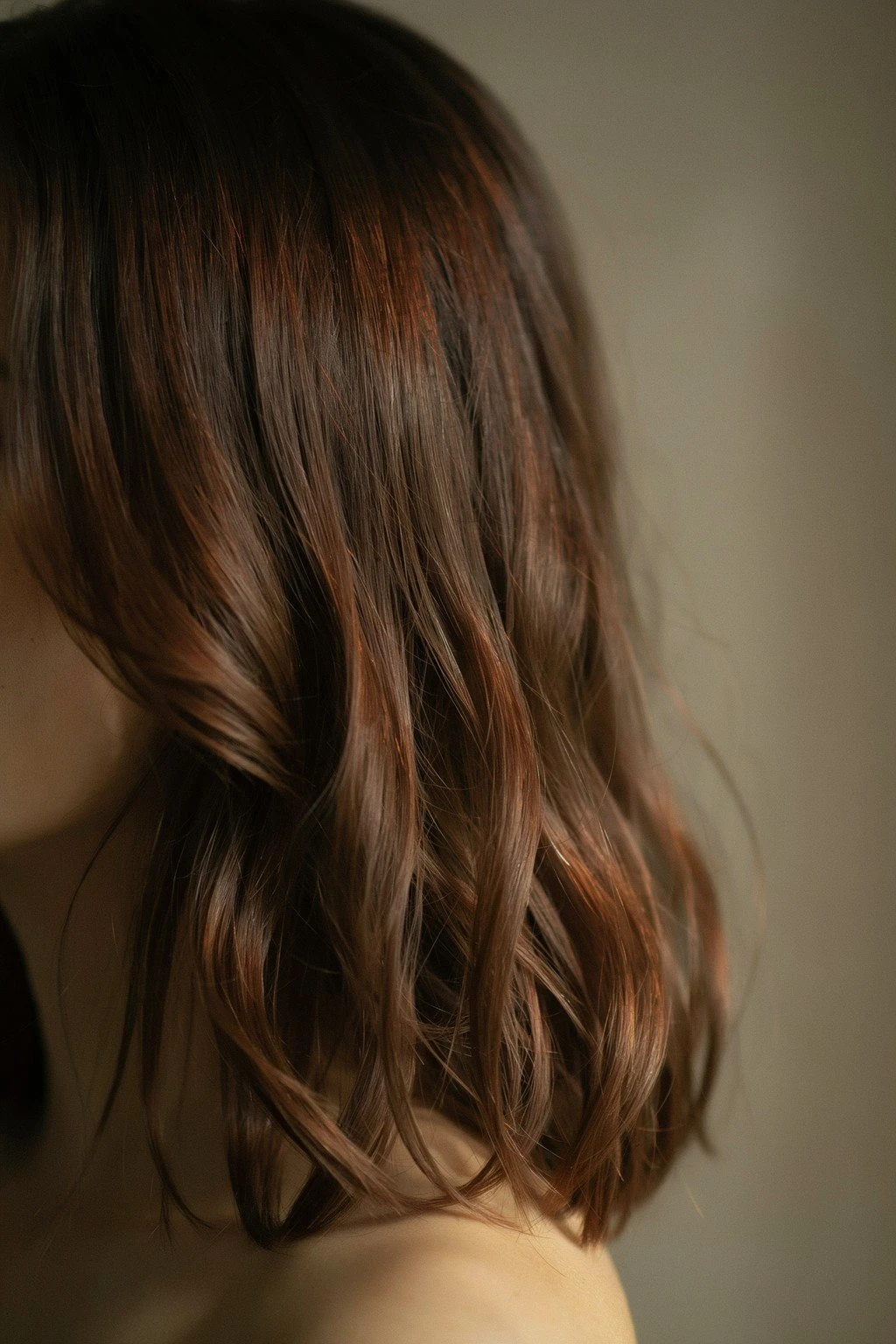 Brunette hair toned deep auburn with warm copper dimension catching directional light