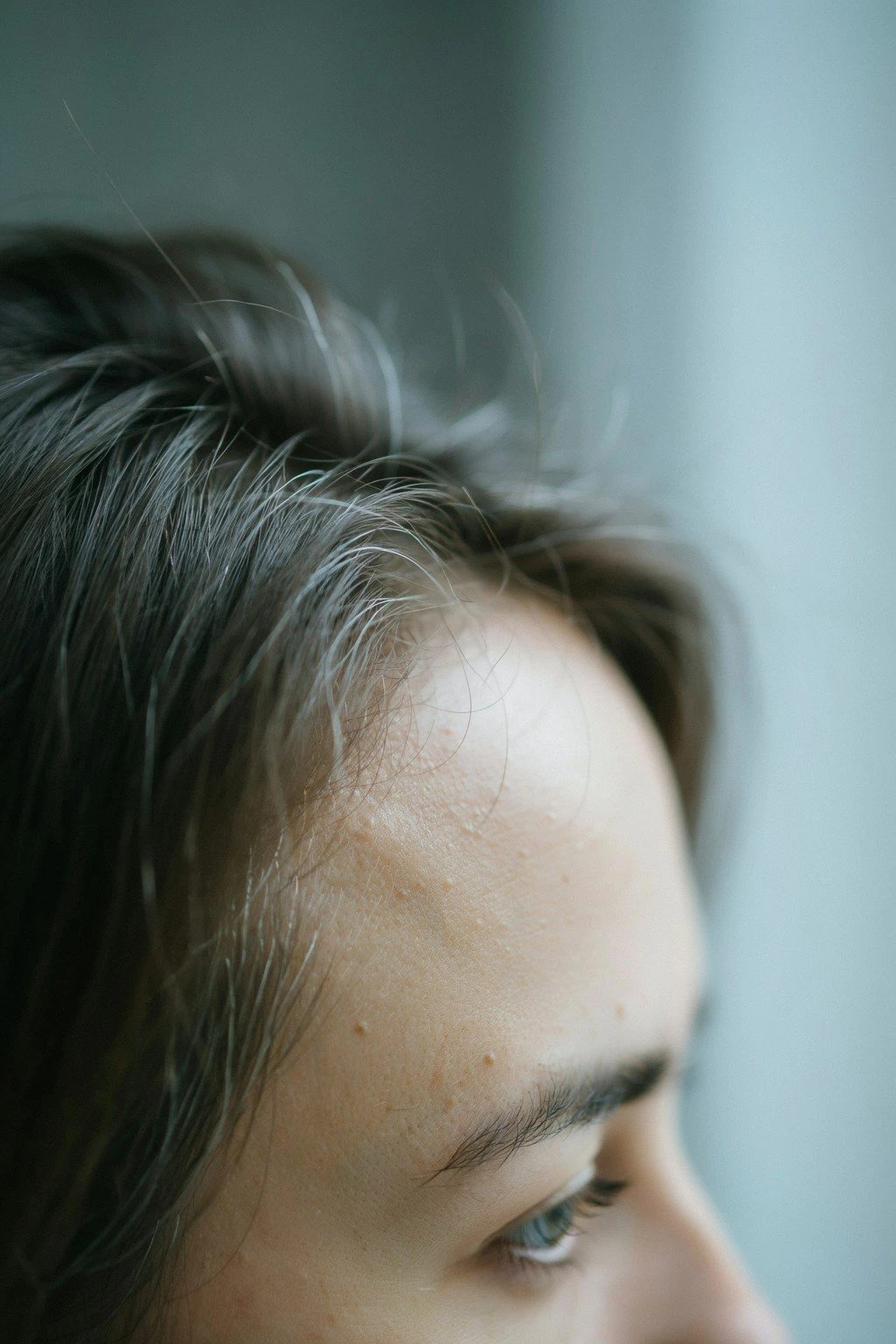 A close view of the first silver strands at the temples against a darker base