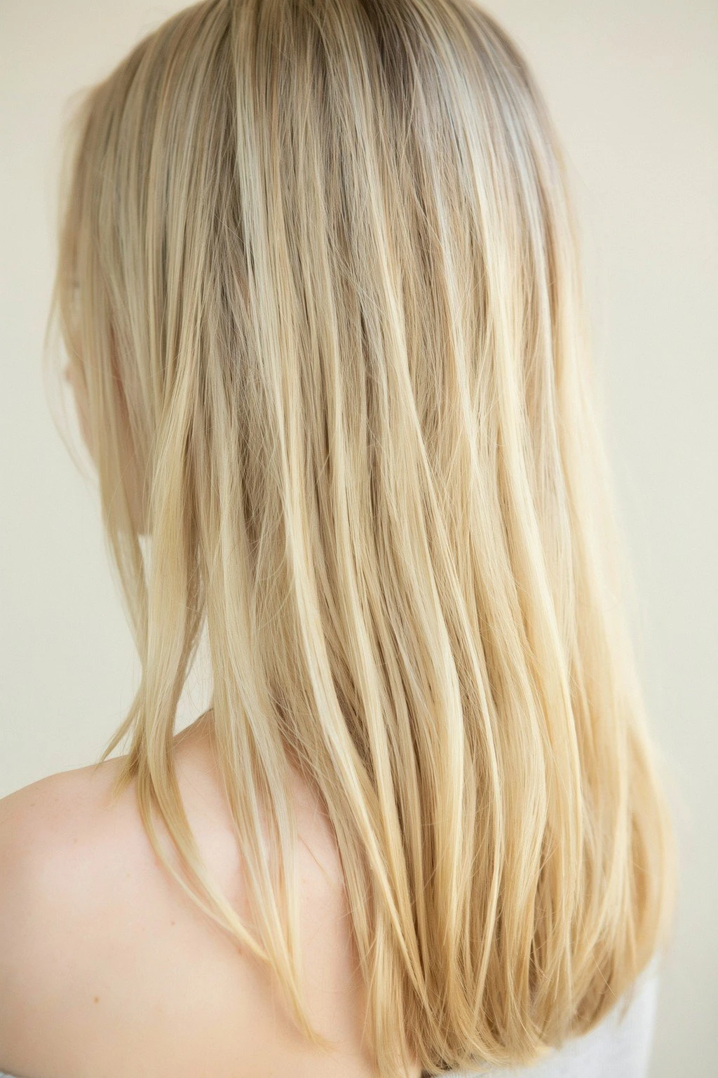 Beige-toned blonde balayage with a soft neutral finish, neither warm nor cool, in diffused daylight