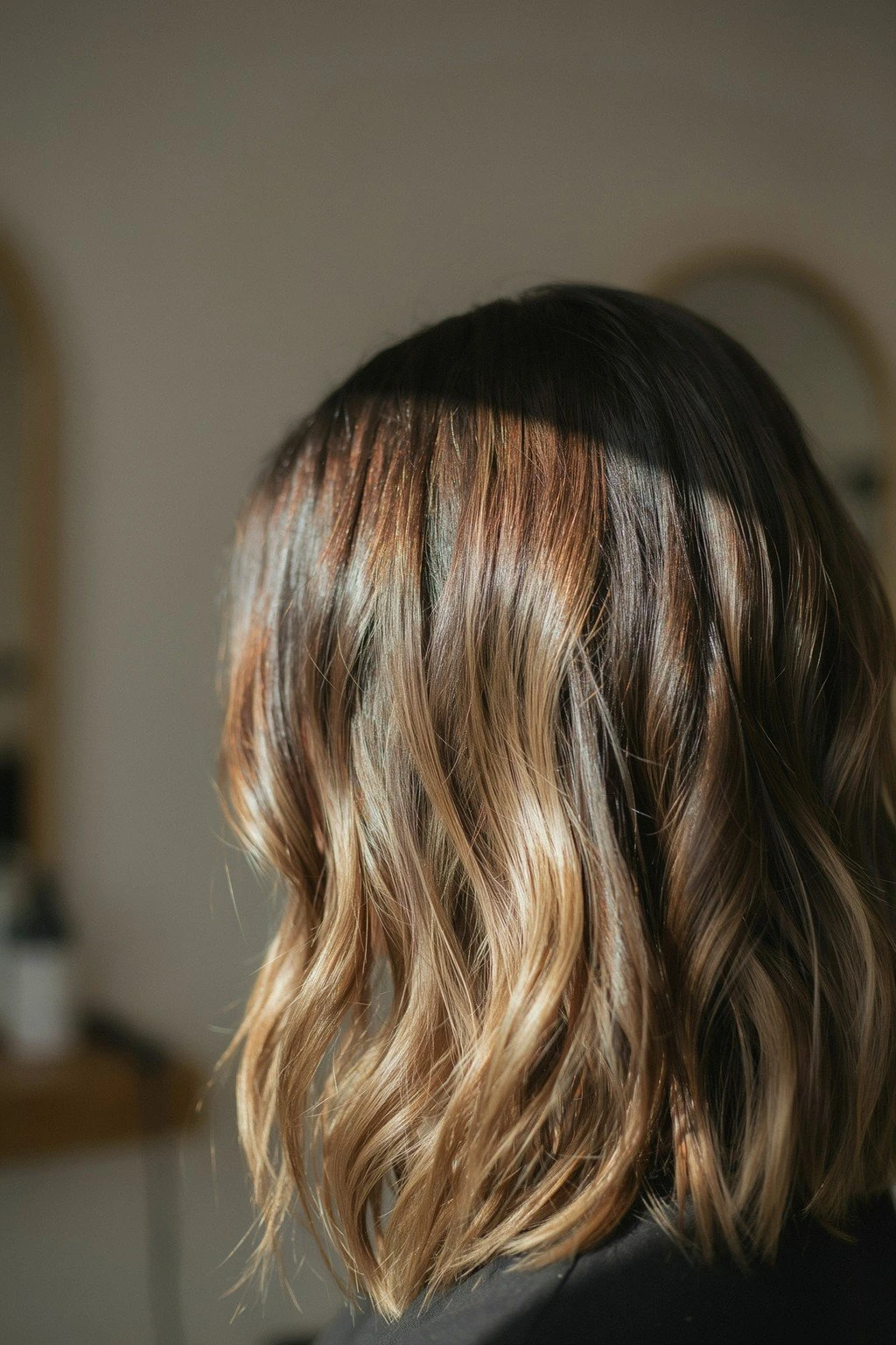 Dark brunette hair with blonde balayage in progress, warm lifted pieces showing against the deep base