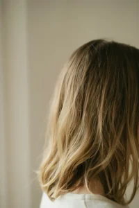 Medium brown hair with soft blended blonde highlights through the mid-lengths, no visible stripe, root left natural