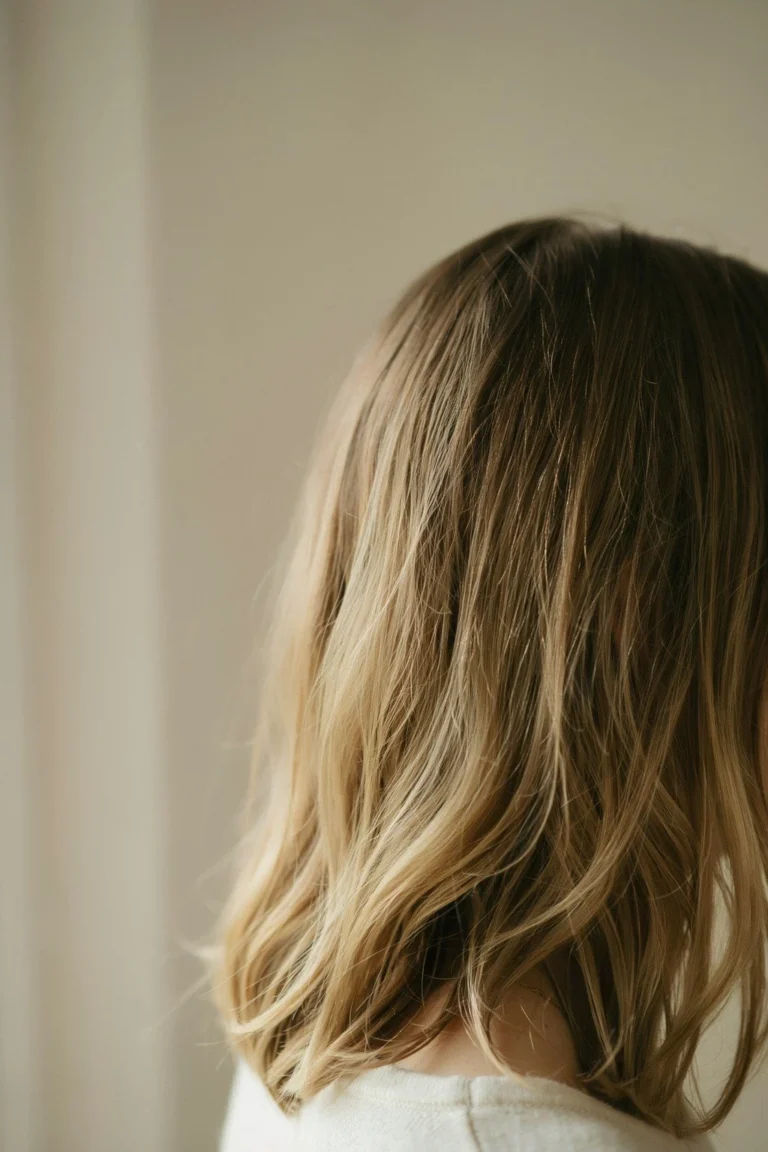 Medium brown hair with soft blended blonde highlights through the mid-lengths, no visible stripe, root left natural