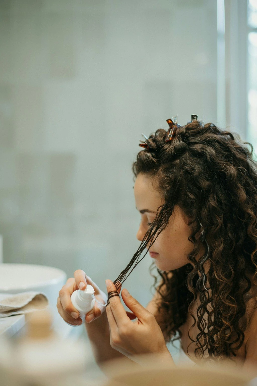 Woman with curly hair being styled with a light product application