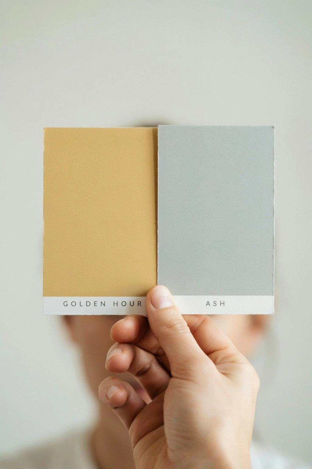 Two swatch cards at the same depth held side by side, one warm golden and one cool ash, showing tone difference at one level