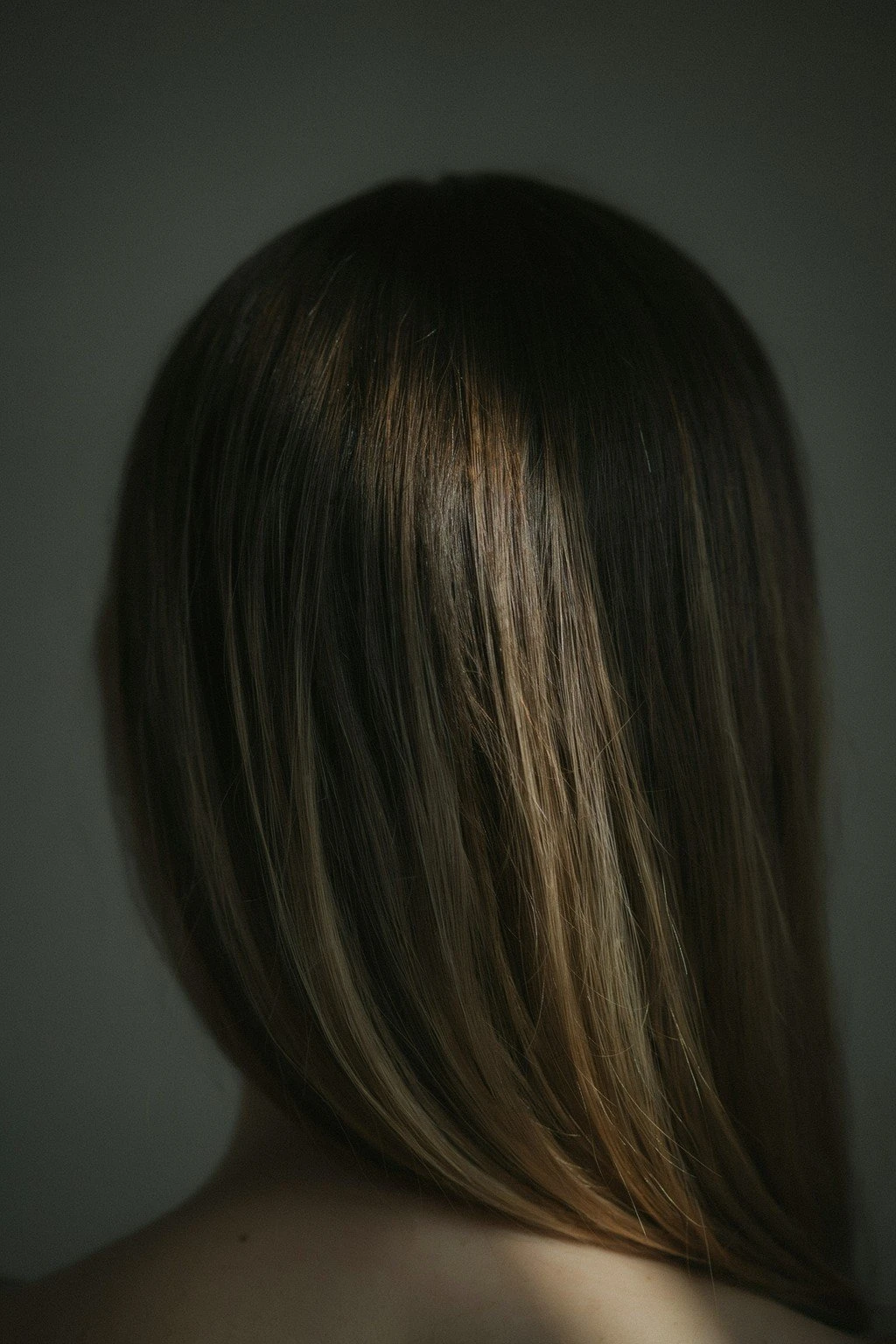 Very dark brunette hair with subtle warm ribbons appearing only from mid-shaft down, most of the head still deep dark base