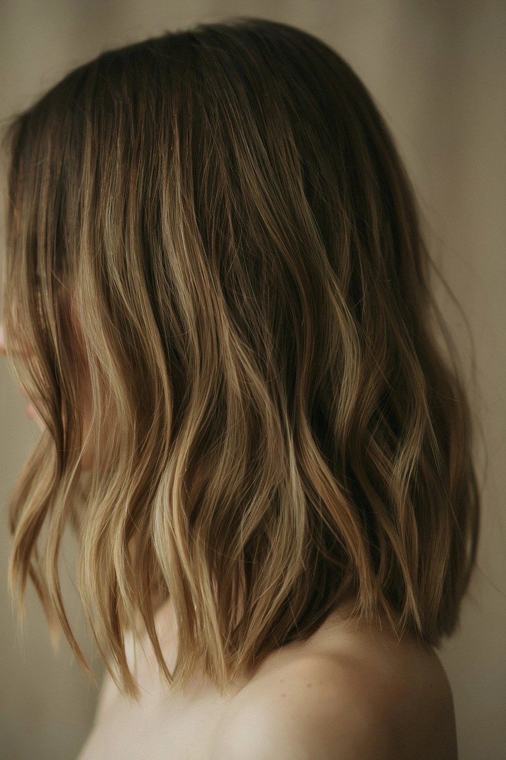 Medium brunette hair melting into warm toffee ends, the gradient catching natural light in a loose wave