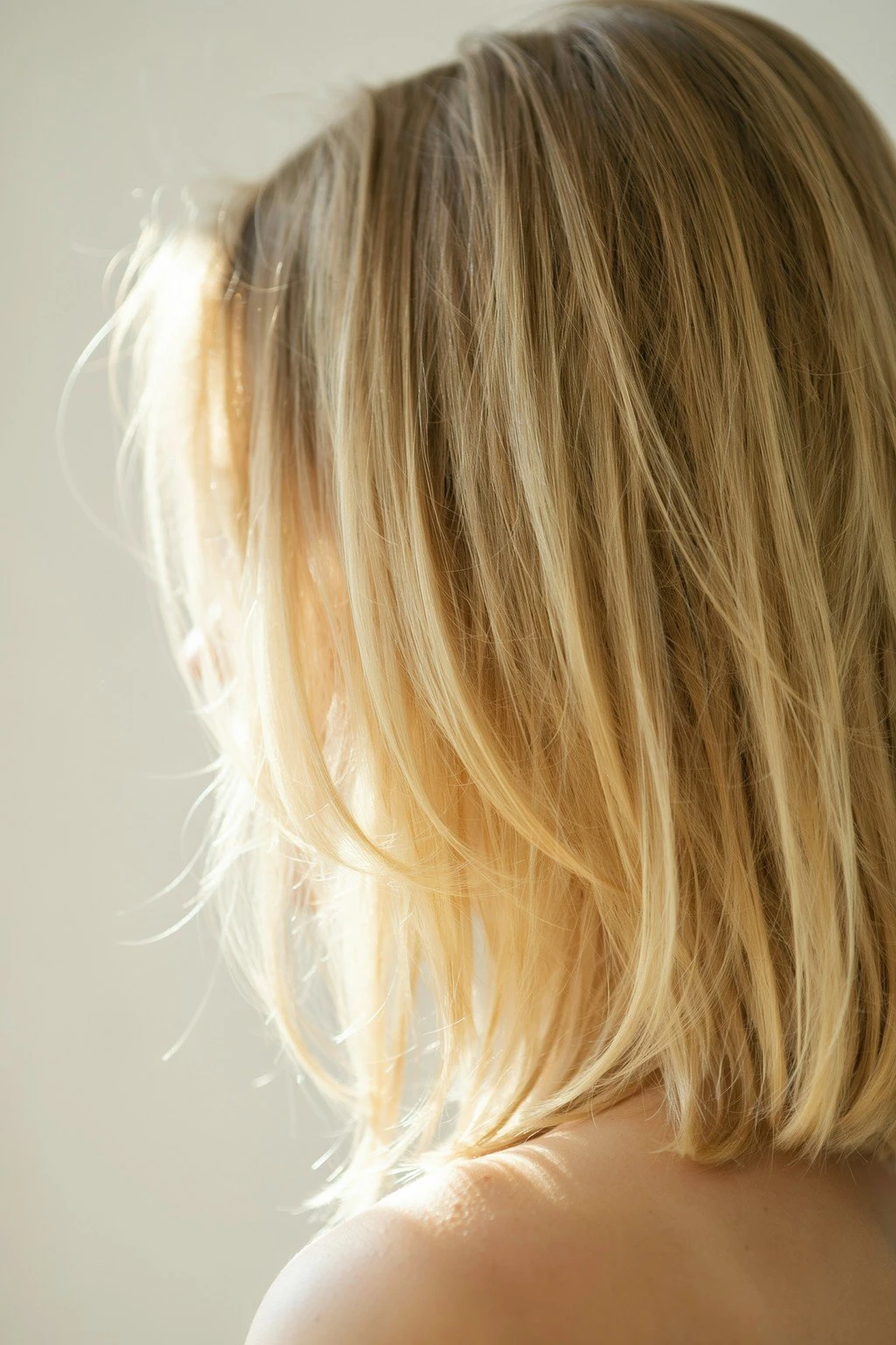 Light brunette hair melting into buttery blonde ends, the gradient seamless and bright in warm natural light